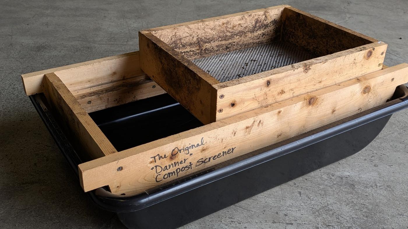 The Danner screener's wooden frame resting across a black mixing tub, with the rolling screen tray sitting on top of it.
